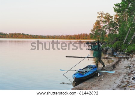 The tourist fishes on sand beach of northern lake