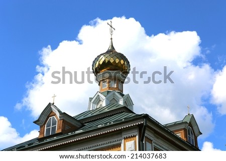 Village church dome against white clouds and blue sky