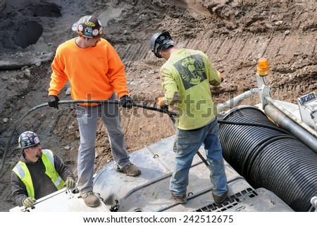 NEW YORK CITY, NEW YORK - APRIL 28, 2014: Three construction workers along the High Line Park. The park\'s popularity has caused a building boom that threatens the views that make the park popular.