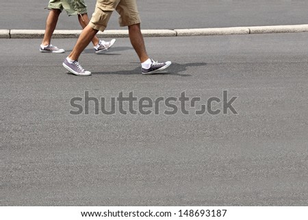Two young men in running shoes, walking down the street