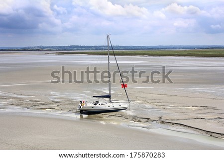 Stranded yacht near the abbey Mont Saint Michel waits tide, to set sail. Normandy, France