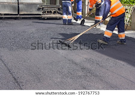 Workers on Asphalting paver machine during Road street repairing works
