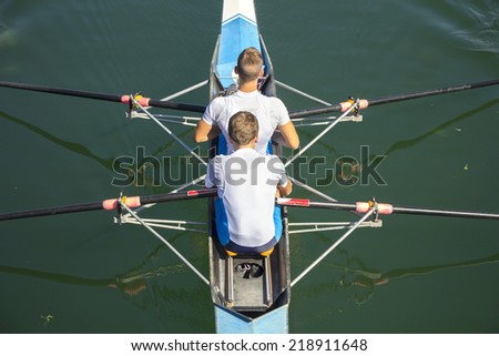 Two rowers in a boat, rowing on the tranquil lake