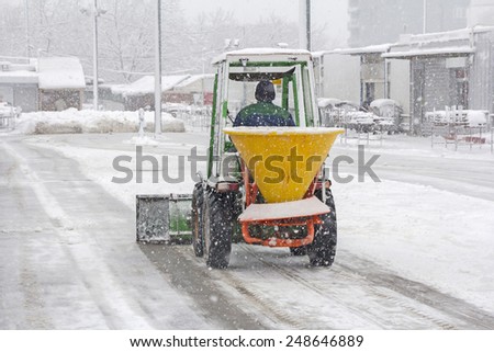 Small snowplow removing snow from sidewalk and sprinkled salt antifreeze