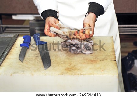 A worker cleaning a fresh octopus in the fishmonger