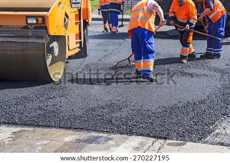 Roller and workers on asphalting and repair of city streets