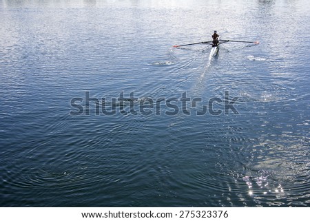 Women Rower in a boat, rowing on the tranquil lake