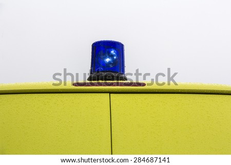 Blue rotating beacon on yellow ambulance car