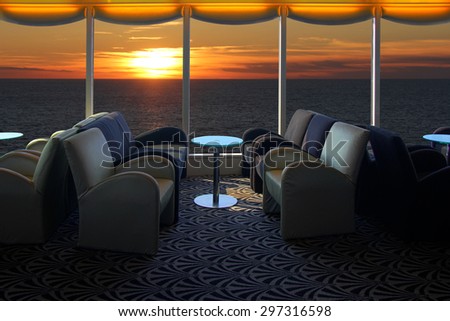 Lounge on a cruise ship, with tables and armchair in the sunset at sea