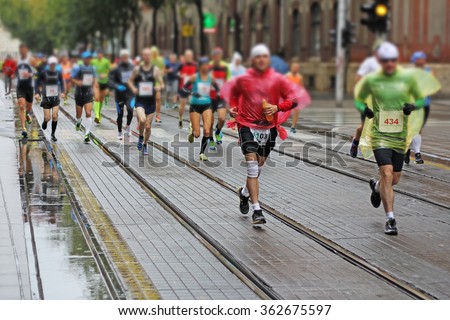 Marathon runners race in city streets, blurred motion