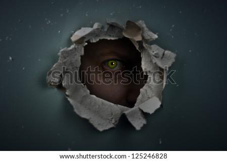 eye behind hole in the wall