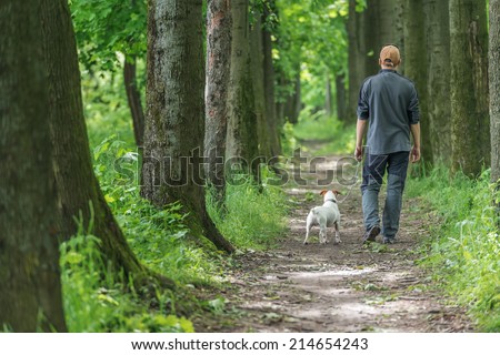 man and dog walking on park