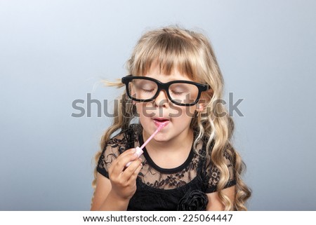 little cheerful girl paints lips with lipstick  mother\'s