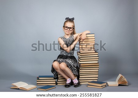 smart girl with a stack of books. Girl with glasses reading a book