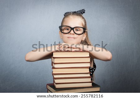 smart girl with a stack of books. Girl with glasses reading a book
