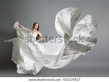 beautiful young girl dancing. The girl in flying white dress. A white cloth is flying in the air. White light dress