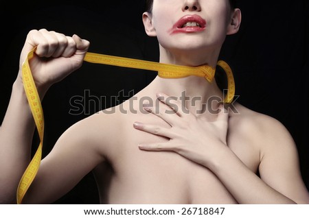 Young woman throttle herself by tape-line. Black background