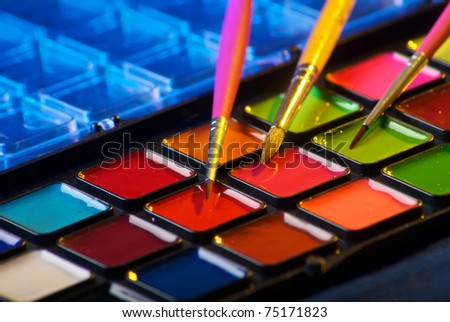 Closeup of a palette of watercolor paints with three brushes