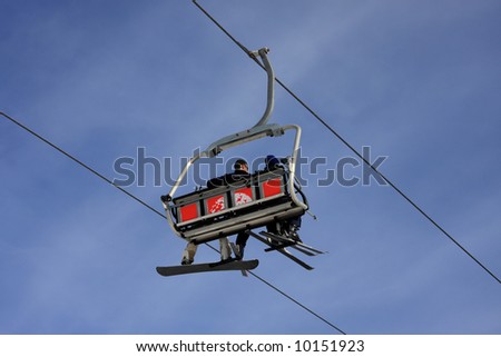 Ski lift chairs with skiers isolated on a blue sky