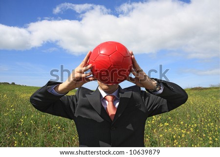 A business man holding a red ball hiding his face