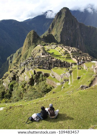 2 tourists looking at the mysterious city of Machu Picchu, Peru