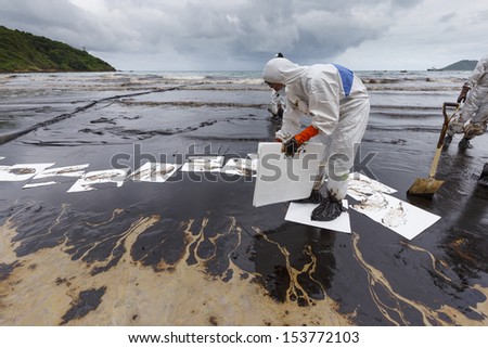 Rayong, Thailand - July 31, 2013: Worker in Biohazard suit placing absorbent paper in a clean-up operation of crude oil spilled at Ao Prao Beach on July 31, 2013 in Koh Samet, Rayong, Thailand.