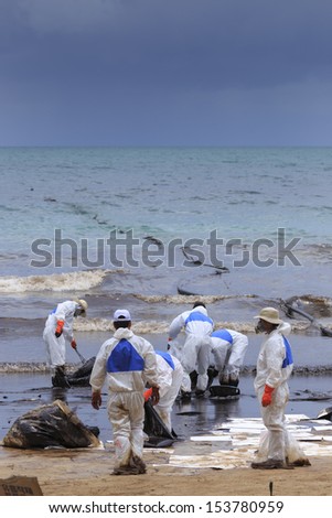 RAYONG, THAILAND - JULY 31, 2013: A worker in biohazard suit during the clean-up operation from crude oil spilled into Ao Prao Beach on July 31, 2013 in Rayong province, Thailand.
