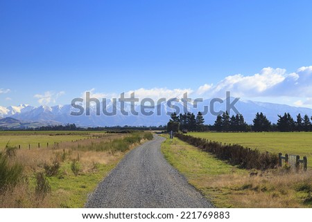 Straight rural gravel road to mountains of the Southern Alps, South Island, New Zealand.