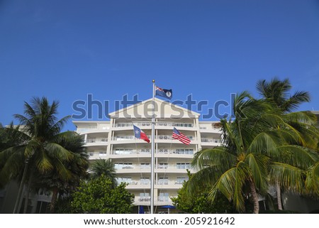 GRAND CAYMAN - JUNE 11: Cayman Islands, United States and State of Texas flags in the front of luxury resort located on the Seven Miles Beach at Grand Cayman on June 11, 2014