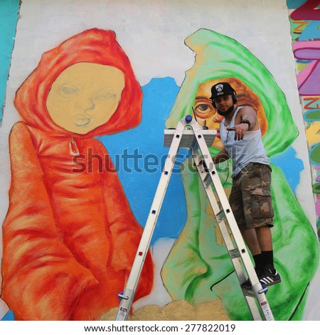 NEW YORK -MAY 12, 2015:Street artist Bob Plater painting mural at JMZ Walls in Brooklyn. A mural is any piece of artwork painted or applied directly on a wall, ceiling or other large permanent surface