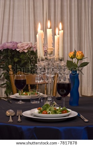 Romantic table for two served with salad. Glasses with wine.