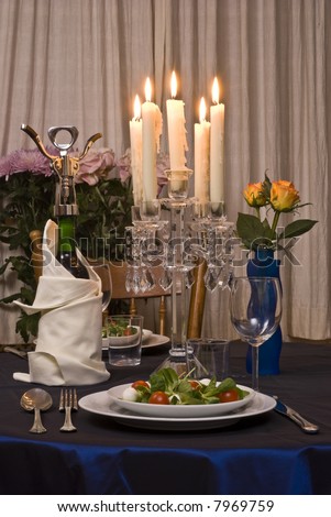 Romantic table for two served with salad. A bottle of wine prepared.