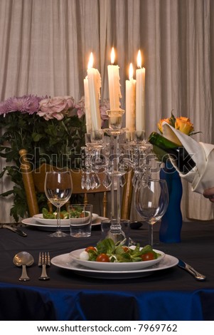 Romantic table for two served with salad. Pouring wine.