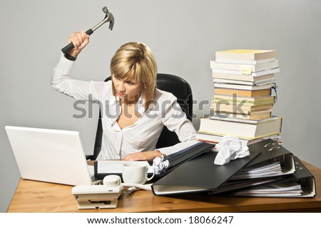 Angry business lady hitting a laptop with a hammer.