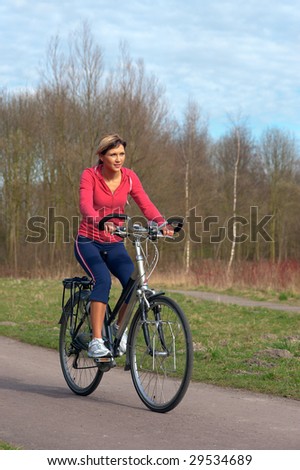 Woman in sports cloths cycling in a park.