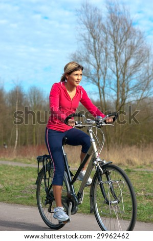Woman in sports cloths cycling in a park.