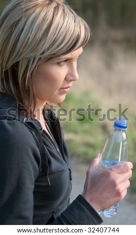Sportswoman drinking water in a park.