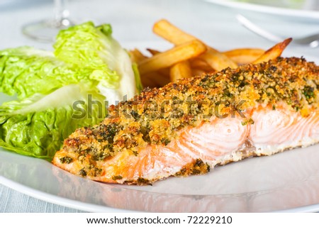 Baked salmon served with chips and salad greens.