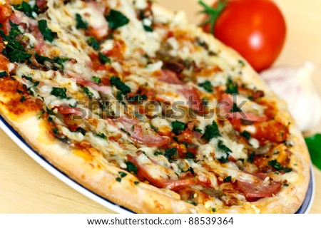 ham, mushroom and vegetable pizza and tomato at the back