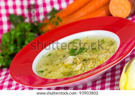 A picture of a  traditional chicken soup served  over vegetable background