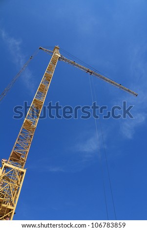 Yellow hoisting crane on blue sky background
