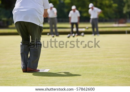 Men playing lawn bowls. Very narrow depth of field. Focus on player.