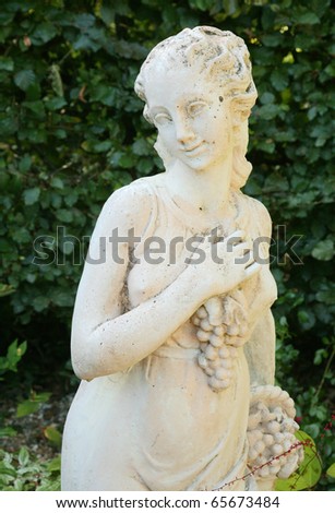Roman or Greek statue in garden holding bunch of grapes