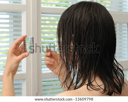 Young woman by the window, with mirror and tweezers in her hand