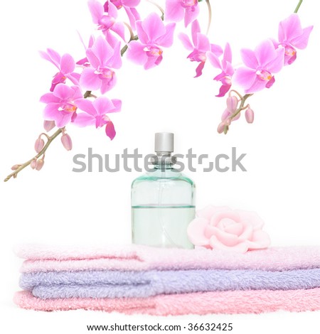 Bathroom set with three towels, a perfume bottle, one rose petal shaped piece of soap and a decorative pink orchid