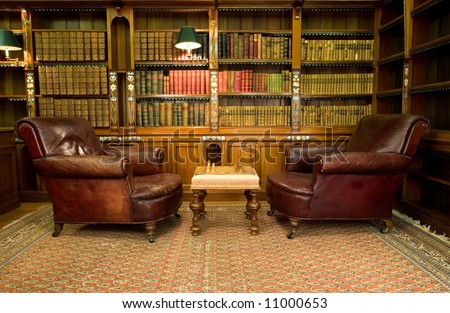 Old studying room with two leather armchairs and chess game