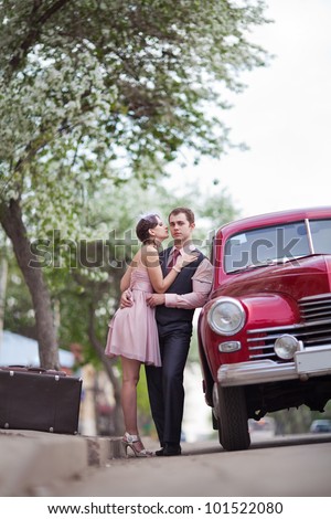 Pretty couple near the vintage car on the sunset background