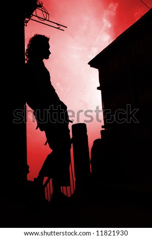 Silhouette of dreaming  long-haired man on the sunset background.