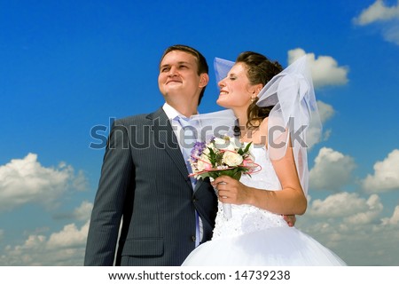 Groom with the bride on the cloudy sky background.
