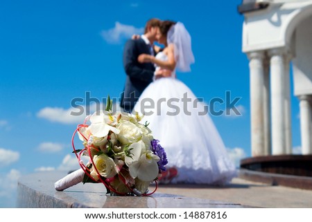 Bride\'s bouquet on the marble. Kissing couple on the background.